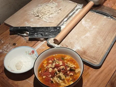 A wooden table with an empty rolling pin, flour in one bowl, and tomato chi.. Stock Photos