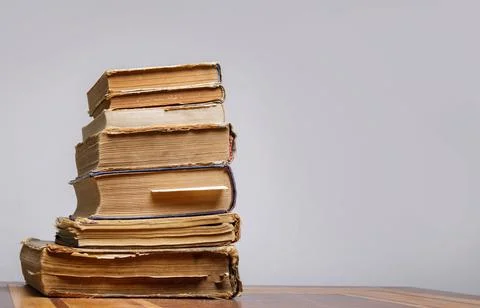 On a wooden table on a gray background a stack of old books with bookmarks Stock Photos