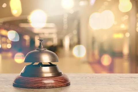 Wooden table with hotel service bell on blurred background. Space for text Stock Photos