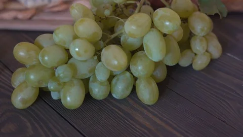 On a wooden table is a large bunch of white grapes. in the background a head of Stock Footage 81944676