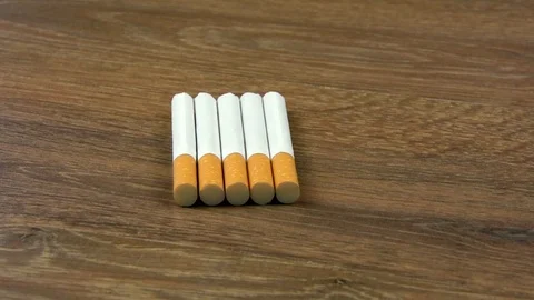 On a wooden table lies five cigarettes. The table is spinning Stock Footage 129943746