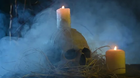 On a wooden table is a skull and candles are burning Stock Footage 123760358