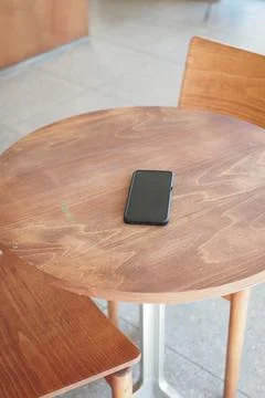 Wooden table with a smartphone in a cafe setting. lost smart phone concept Stock Photos