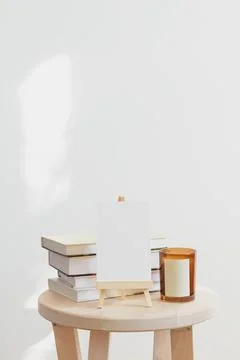 Wooden table with stack of books and candle in glass, mock up white sign for  Stock Photos