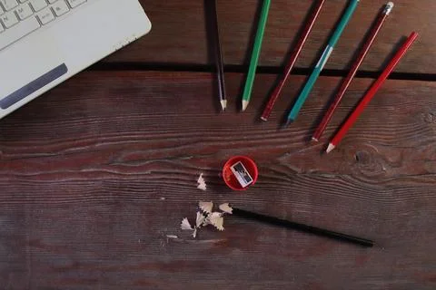 On the wooden table there is a red sharpener and pencil shavings. Stock Photos
