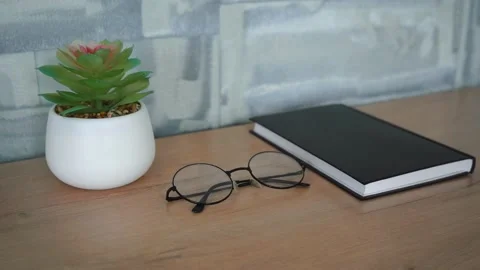 Wooden table on which lies a notebook, glasses and a flower Stock Footage 140617105