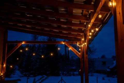 Wooden Terrace with LED String Lights in a Snowy Winter Setting Foto stock