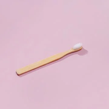 Wooden toothbrushe with shadows on a pink background Stock Photos