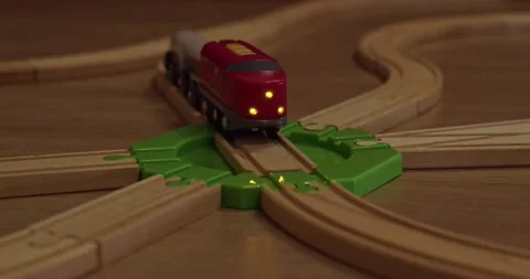 A wooden train set featuring vibrant green tracks alongside an illuminated train Stock Footage 297692263