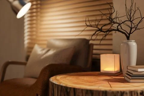 Wooden tree stump side table with books and vase aside armchair with pillow.. Stock Illustration