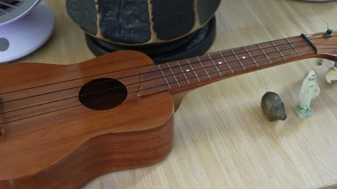 Wooden ukulele resting on table in cozy indoor setting Stock Footage 346350075