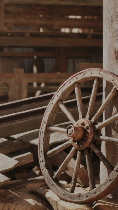 Wooden wagon wheel in a rustic barn setting during daylight hours Stock Footage 339044693