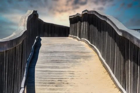 Wooden walkway bridge covered with sand, leading to infinity point Stock Photos