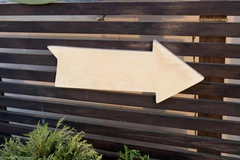 A wooden white arrow pointer with no inscription on a brown plank background Stock Photos