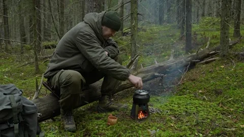 Woodsman makes coffee in the forest over a fire 動画素材 295447384