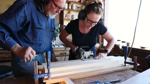 Woodwork biscuit joining timber older gentleman training lady assistant Stock Footage 231788559