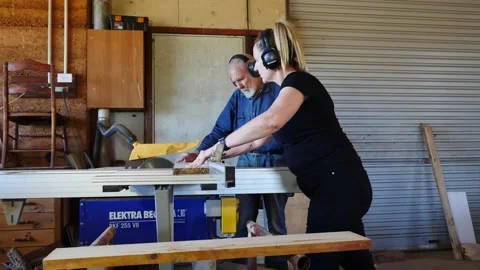 Woodwork table saw timber older gentleman training lady assistant Vidéo 231788037