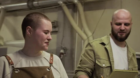 Woodworker and Apprentice Walking through Workshop, Discussing Notes on Notepad Stock Footage 292794984