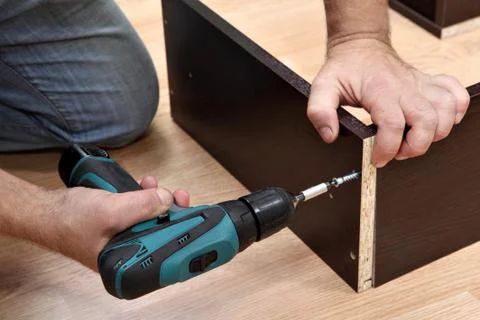 Woodworker Assembling Furniture made of chipboard using a cordless screwdrive Stock Photos