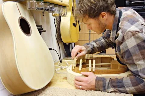 Woodworker building guitar in workshop Stock Photos