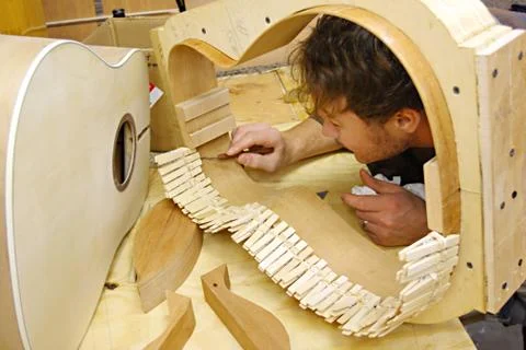 Woodworker building guitar in workshop Stock Photos