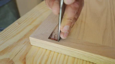Woodworker carving a mortise with a chisel in a piece of hardwood. The craftsman Видео 320147019