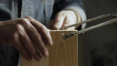 Woodworker cuts out a dovetail on a pine board with a hand jigsaw. Stock Footage 166340988