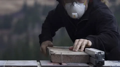 Woodworker with Goggles and Mask Cuts Board on Saw Stock Footage