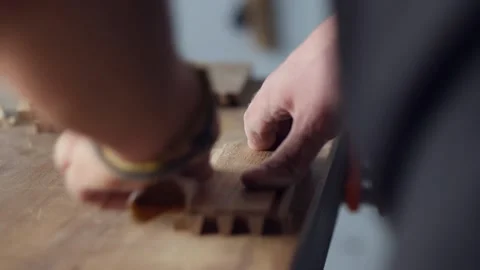 Woodworker grinds the grooves on the wood piece with sandpaper for further bo Stock Footage 144244853