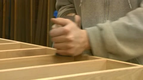 A woodworker hand-planes a wood project Stock Footage