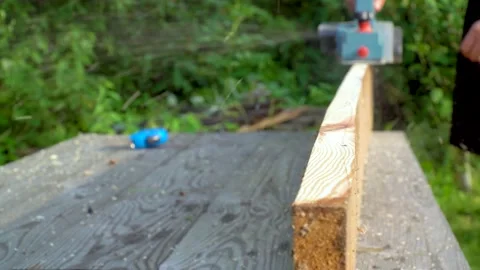 Woodworker hands planks a pine plank with an electric planner on a country plot Vídeos de archivo 146983991