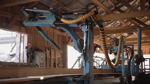 Woodworker in helmet cutting timber log on industrial saw machine Stock Footage 85476655