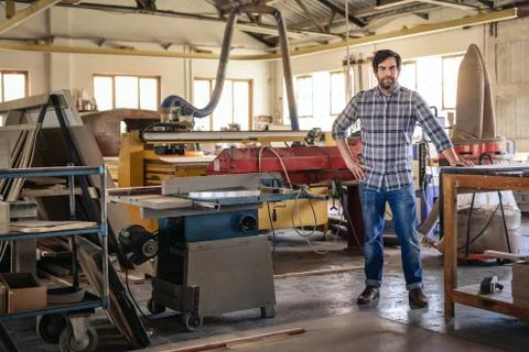 Woodworker leaning on a table in his large workshop Stock-Fotos