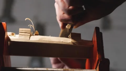 Woodworker remove the excess from a piece of wood with a knife Stock Footage 147873440