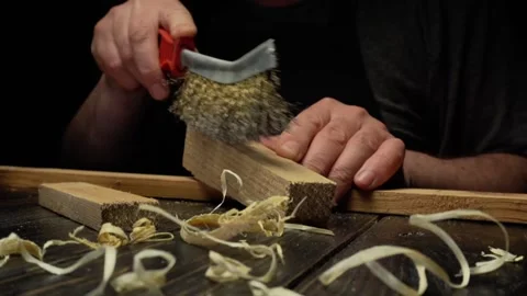 Woodworker scrapes wood surface with wire brush, revealing smooth texture while Stock Footage 333308035