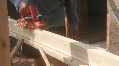 A woodworker uses an electric planer to smooth the surface of a wooden Stock Footage 333345297