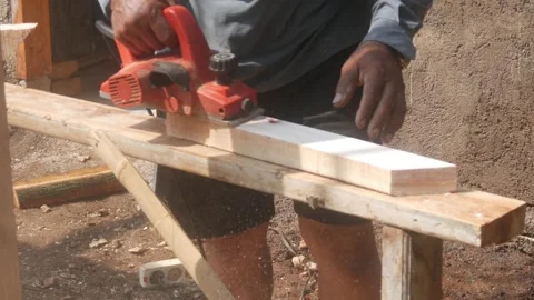 A woodworker uses an electric planer to smooth the surface of a wooden Stock Footage 333345342