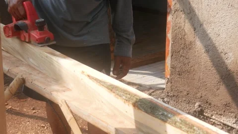 A woodworker uses an electric planer to smooth the surface of a wooden Stock Footage 333345350