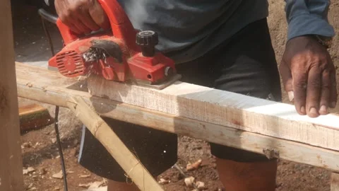 A woodworker uses an electric planer to smooth the surface of a wooden Stock Footage 333345353