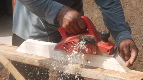 A woodworker uses an electric planer to smooth the surface of a wooden Stock Footage 333345392