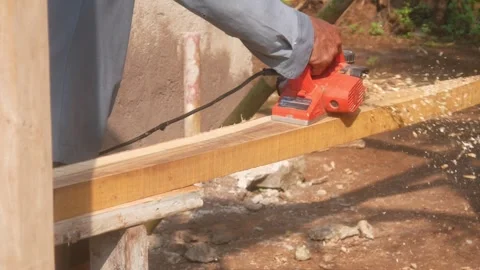 A woodworker uses an electric planer to smooth the surface of a wooden Stock Footage 333348544