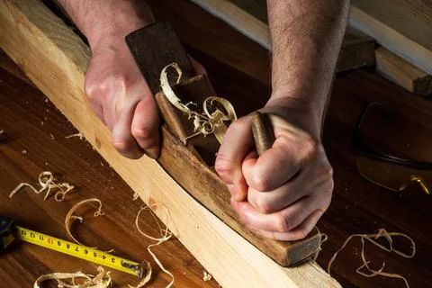 Woodworker using a hand plane to clean up a wooden board. Hands of the master Stock Photos