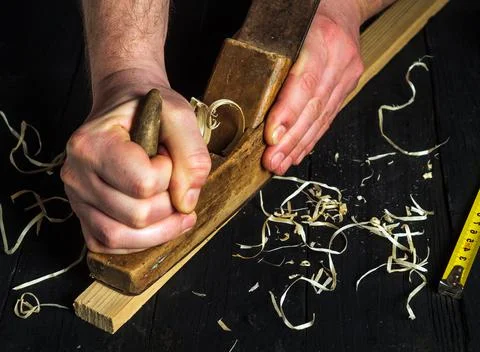 Woodworker using a hand plane to clean up a wooden board. Hands of the master Stock Photos
