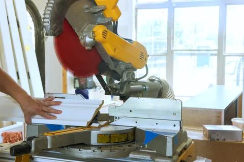 Woodworker using miter saw in workshop to cut molding during works day for home Stock Photos