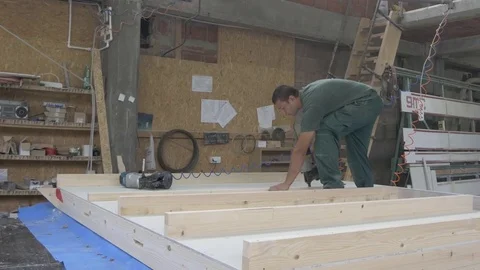 Woodworker using pneumatic gun to hammering nails to wooden construction. Stock Footage 79857331