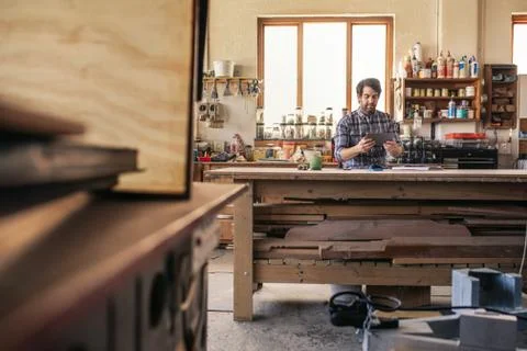 Woodworker using a tablet while sitting at his workbench Stock Photos