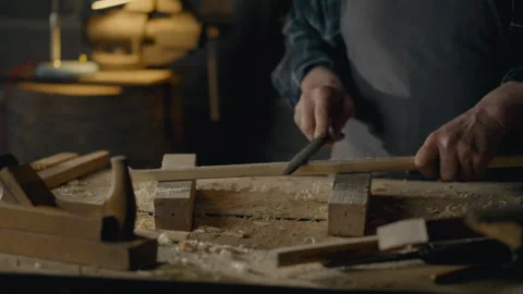 A woodworker works with a hand tool to process a piece of solid wood a woodw Stock Footage 249843510