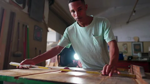 Woodworking apprentice measuring piece of wood in preparation for slicing w.. Video stock 246767616