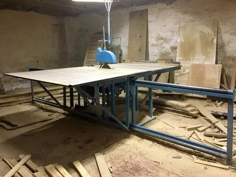 Woodworking area features a large table saw and wooden materials in a works.. Фото