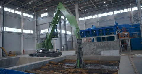 In a woodworking plant, a loader picks up logs from the water and transfers them Stock Footage 161979526